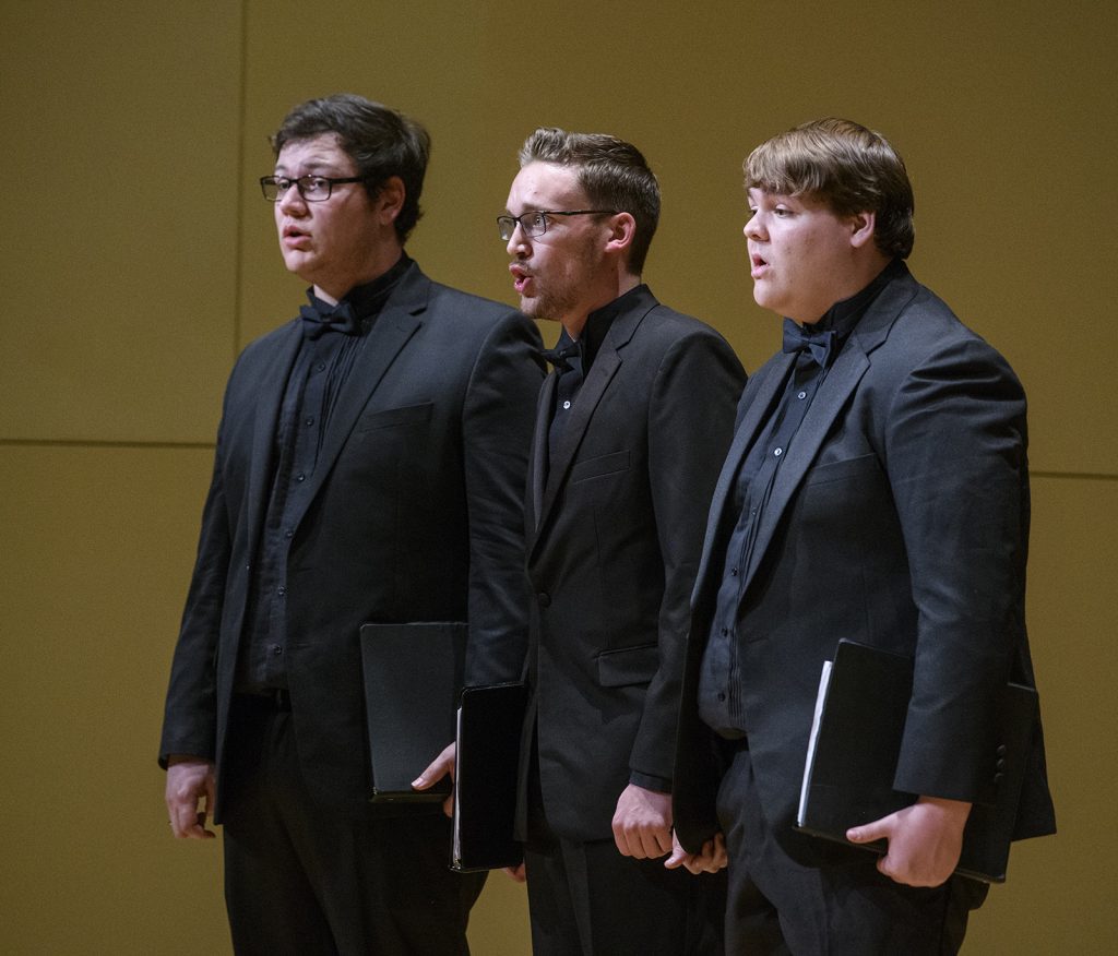 Justin Merriman performs on stage during a choral concert.